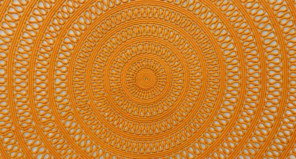 Round Shang Rug, yellow cord in zig zag like pattern on a white background.