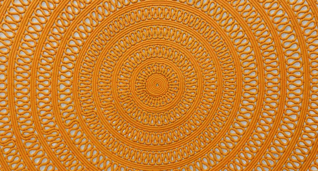 Round Shang Rug, yellow cord in zig zag like pattern on a white background.