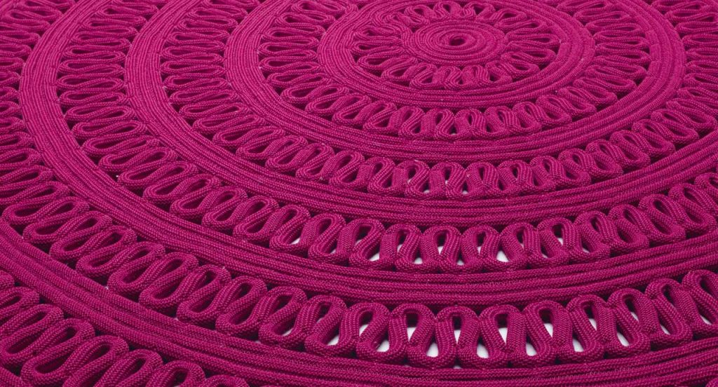 Round Shang Rug, pink cord in zig zag like pattern on a white background.
