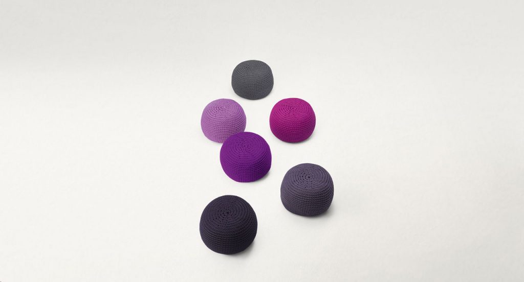 Six Picot Indoor Poufs, round shape, upholstery in wool cord, three in grey. two in purple and one in pink on a white background.