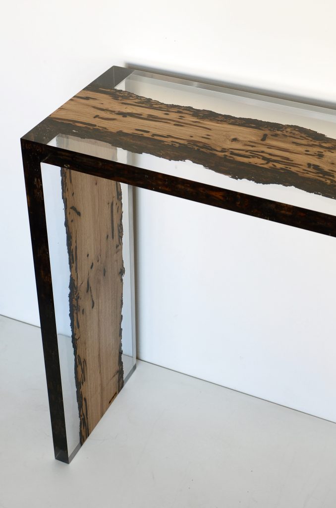Closeup of Bent River Console with an elongated shape, made of solid wood with a natural finish and featuring a transparent resin inlay, on a white background.