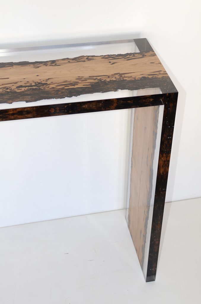 Closeup of Bent River Console with an elongated shape, made of solid wood with a natural finish and featuring a transparent resin inlay, on a white background.