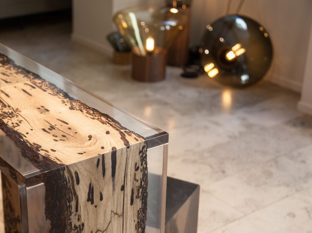 Closeup of Bent Console with an elongated shape, made of solid wood with a natural finish and featuring a transparent resin inlay, in a showroom.