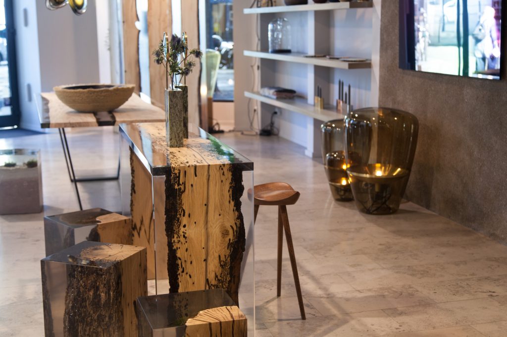 Bent Console with an elongated shape, made of solid wood with a natural finish and featuring a transparent resin inlay, in a showroom.