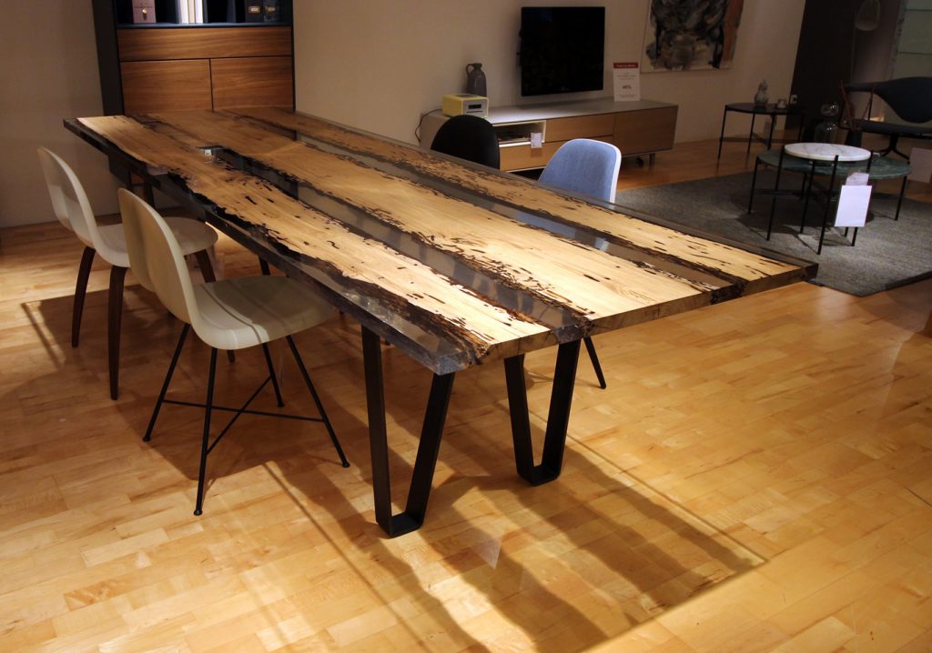 Chimenti Table with an elongated, organic shape, made of solid wood with a natural finish and featuring a transparent resin inlay, in a living room.