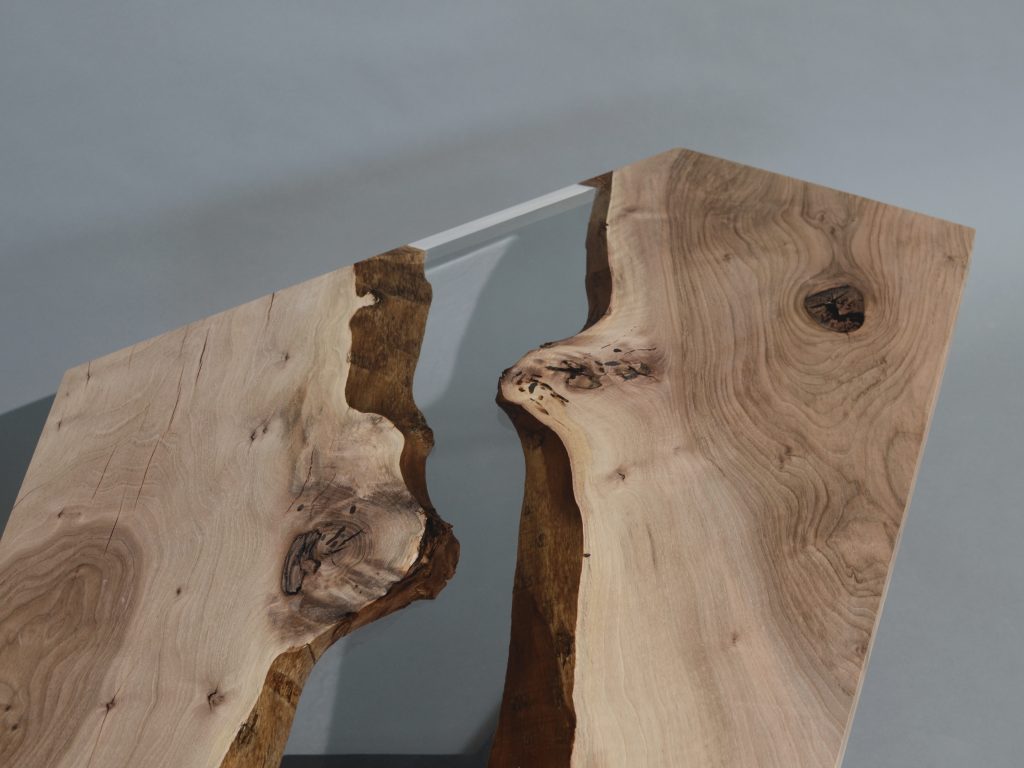 Closeup of Crystal Walnut Low Table with a polygonal shape, made of solid walnut wood with a natural finish and featuring a transparent resin inlay, set against a white background.