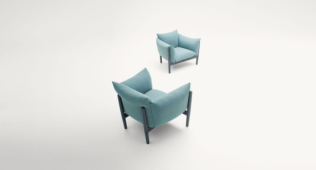 Tapio Armchair, upholstery in blue fabrics, structure and four chairs in black wooden on a white background.