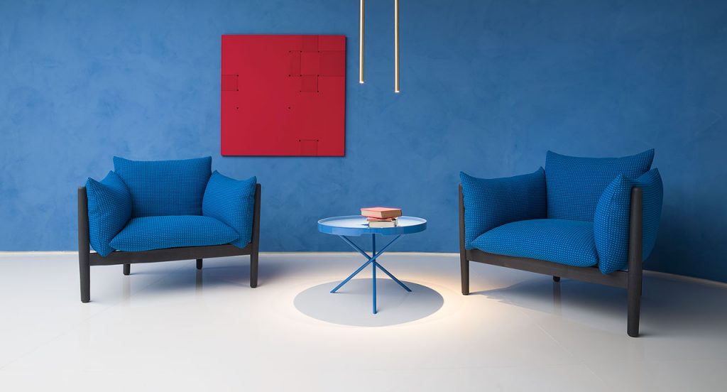 Tapio Armchair, upholstery in blue fabrics, structure and four chairs in black wooden in a living room.