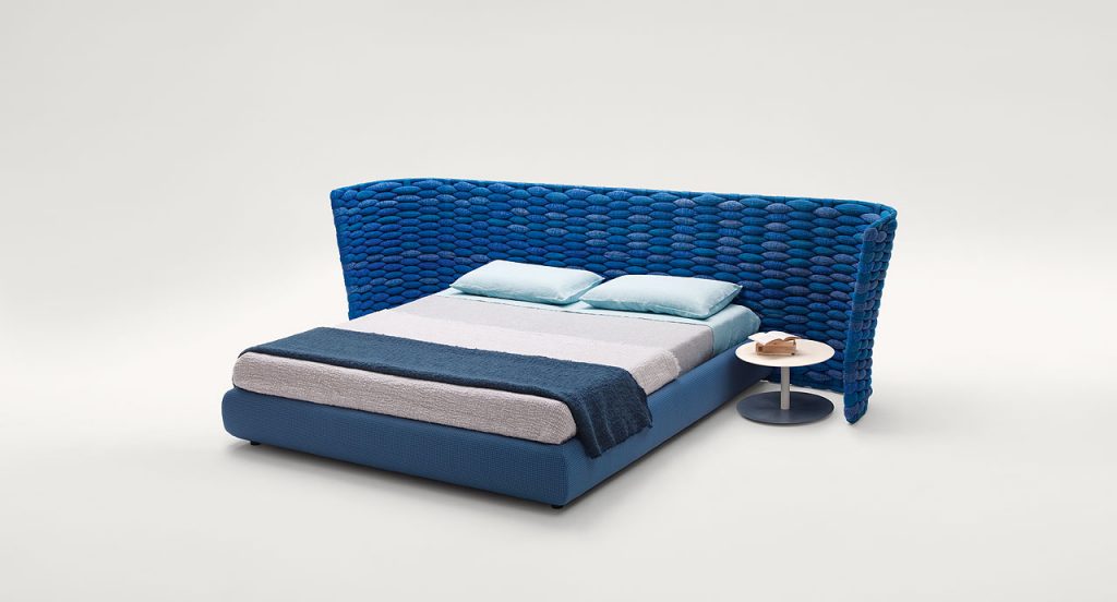 Silent bed with headboard. Cover in blue fabric , headboard in blue chain tubular polyester knit on a white background.