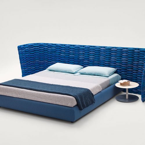 Silent bed with headboard. Cover in blue fabric , headboard in blue chain tubular polyester knit on a white background.