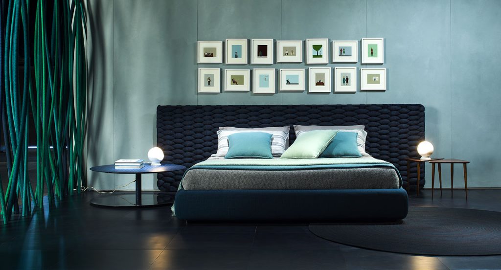 Silent bed with headboard. Cover in blue fabric , headboard in blue chain tubular polyester knit in a bedroom.