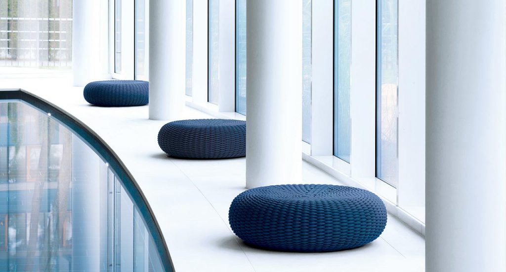 Three Shell poufs, upholstery in blue rope nexto to an indoor pool.