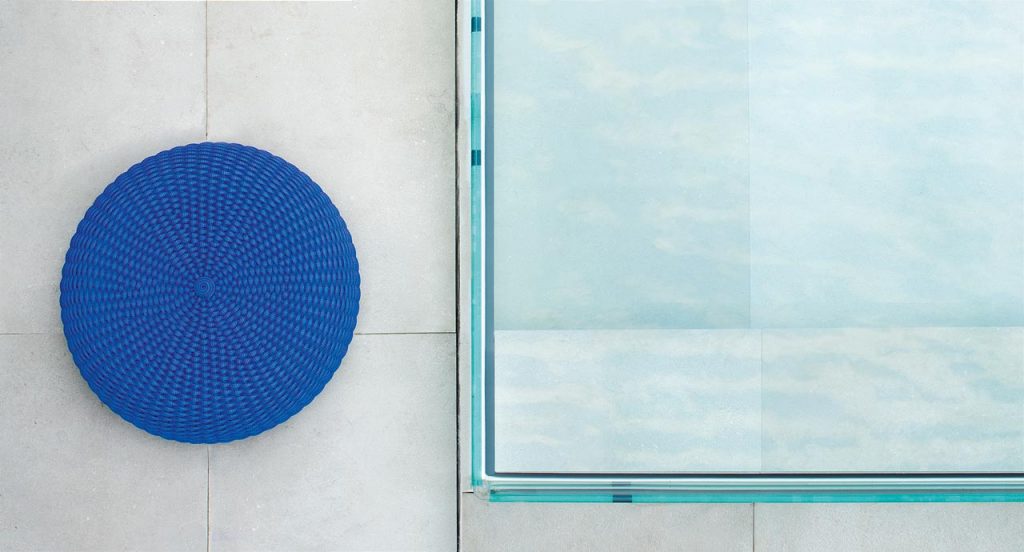 Shell pouf, upholstery in blue rope next to to a pool.