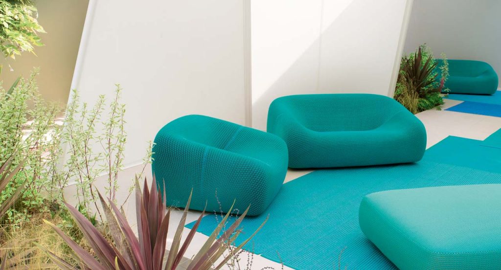 Smile Outdoor Armchair, upholstered in blue aero fabric in a living room.