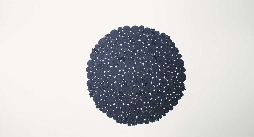 Spin off rug, made of blue sewn spirals on a white background.