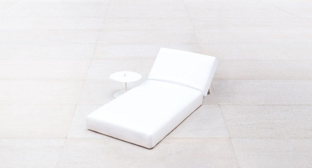 White round Strap side table. Aluminium structure next to a sun bed on a white background.