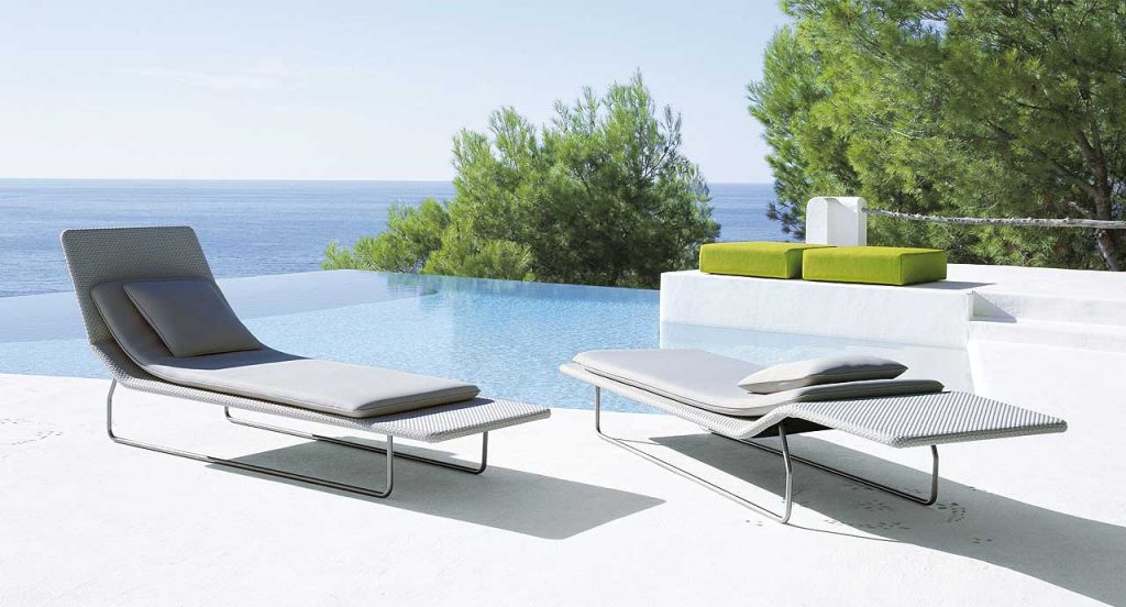 Two Surf sun beds with backrest, structure in steel, upholstery in grey next to a outdoor pool.