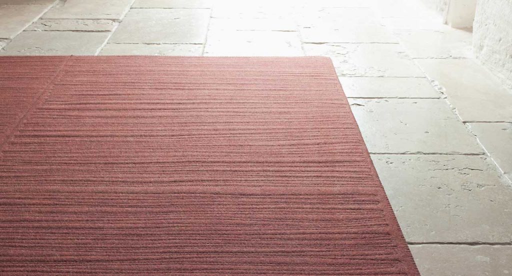 Pink Tatami rug, embriordey of series of parallel, irregular lines on a white floor.