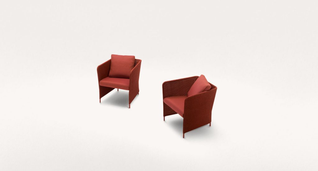 Two red Teatime Armchairs, upholstery in Thuia fabric, two cushions and four steel legs on a white background.