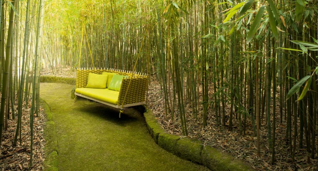 Green lawn swing covered with rope yarn, cushion upholstery in the countryside.