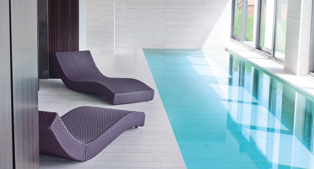 Two brown Wave chaise loungers in rope cord next to an indoor pool.