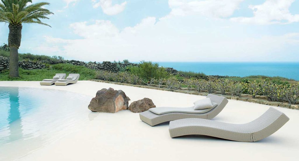 Four grey Wave chaise loungers in rope cord next to an outdoor pool.