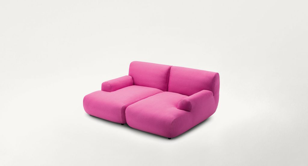 Pink Welcome modular seating system with armrest backrest, two seats and a pouf on a white background.