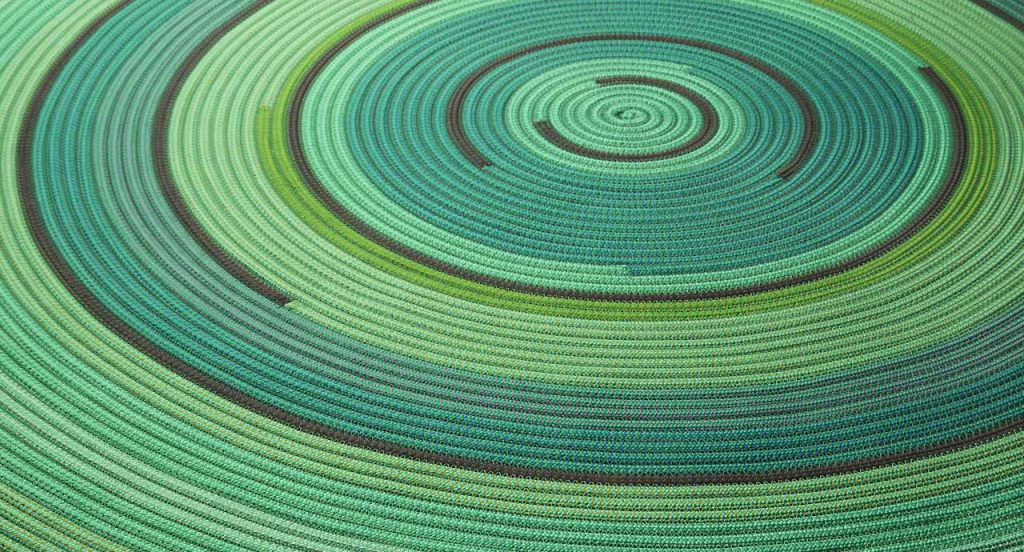 Zoe Rev rug in green, blue and brown cords in a spiral-like pattern.