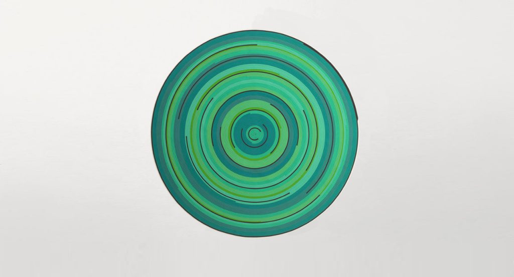 Zoe Rev rug in green, blue and brown cords in a spiral-like pattern on a white background.