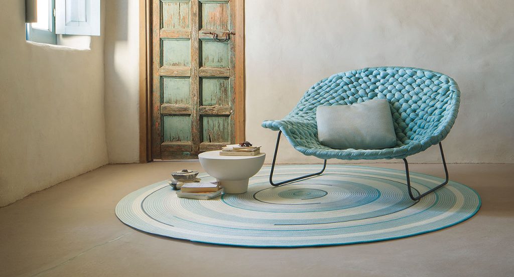 Zoe Rev rug in grey, white, blue and brown cords in a spiral-like pattern in a living room.