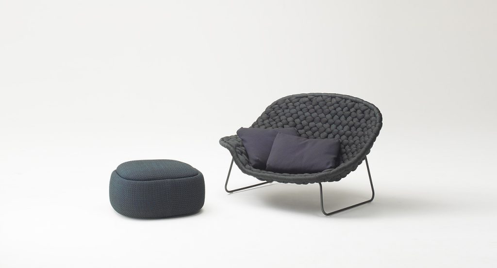 Grey Shito Indoor Pouf, upholstery in fabric nexto to a chair on a white background.