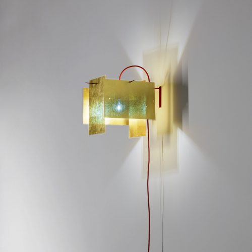 A 24 Karat Wall light that is on a while wall perpendicular to the wall