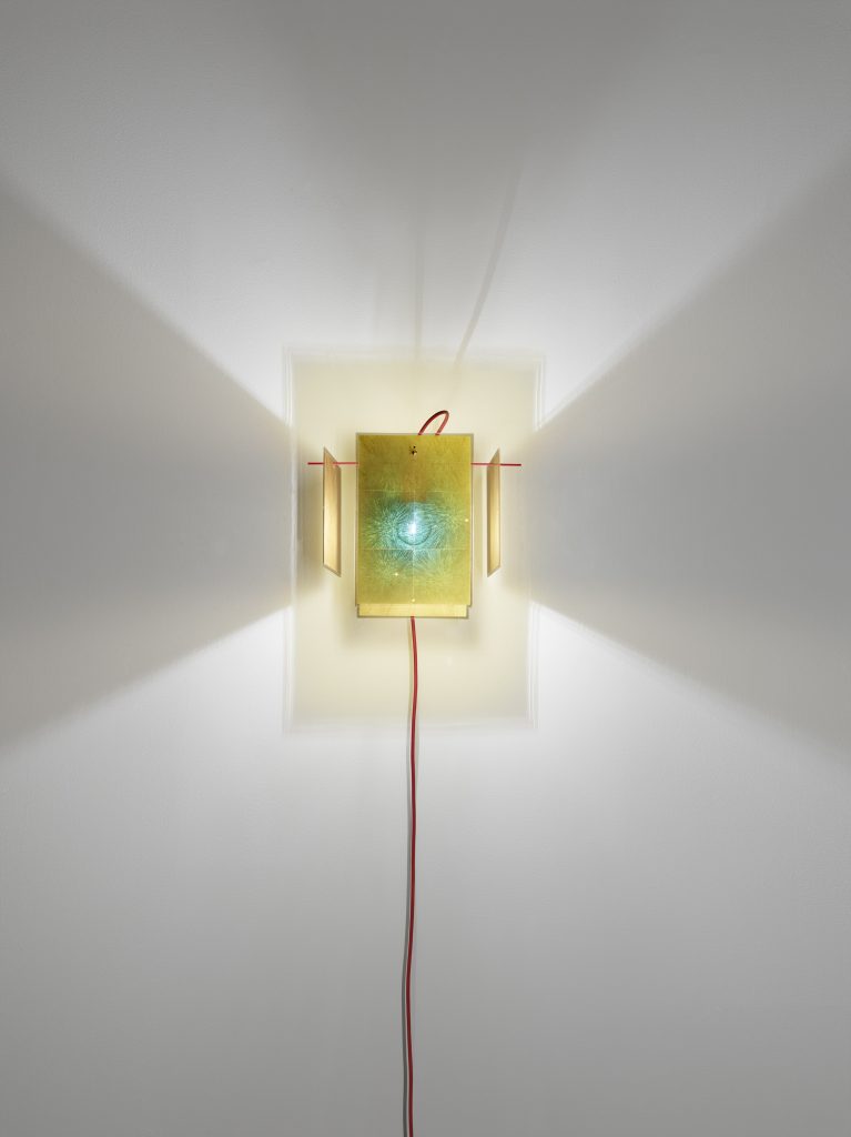 A 24 Karat Wall light that is on a while wall facing vertically