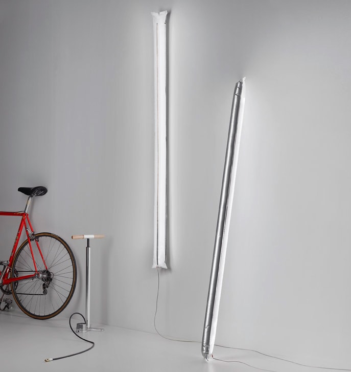 A bike parked next to a white wall with Blow Me Up lights hanging on a wall in a room