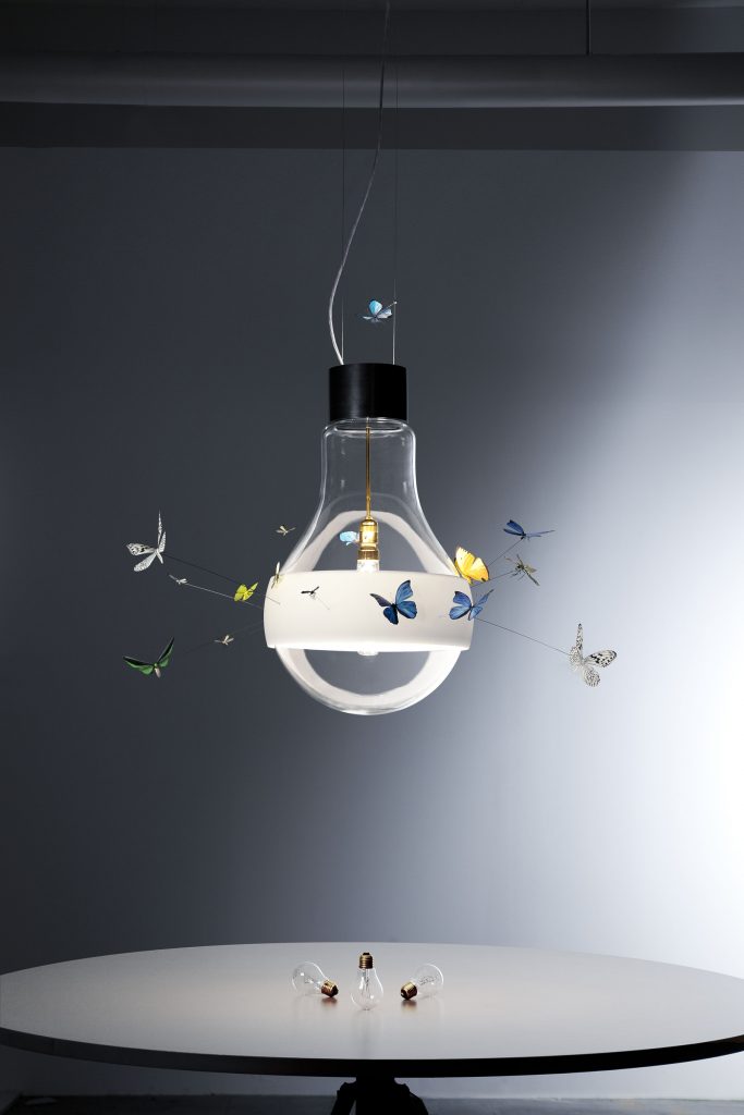 Butterflies dreaming shows a lightbulb with butterflies surrounding it over a table