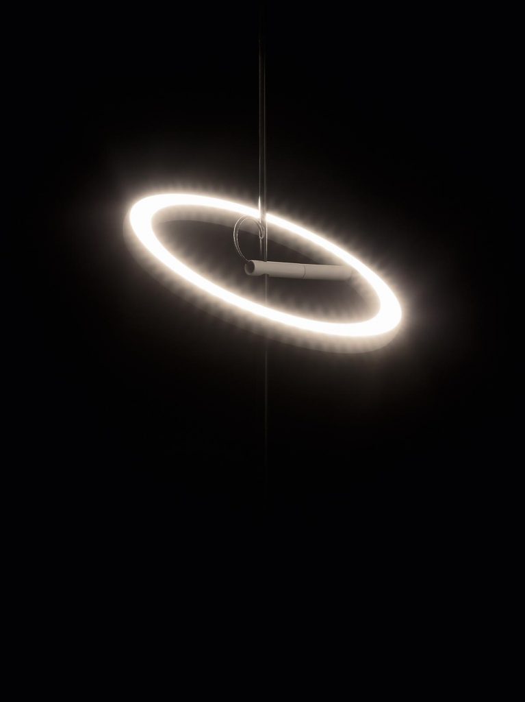 A Ringelpietz hanging from a ceiling in front of a black background illuminated
