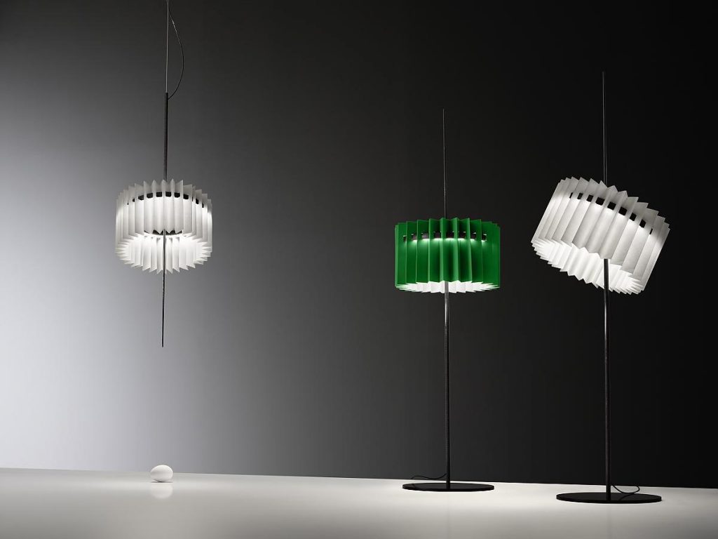 A couple of Ringelpietz lamps sitting on top of a table with one hanging from the ceiling in front of a grey background