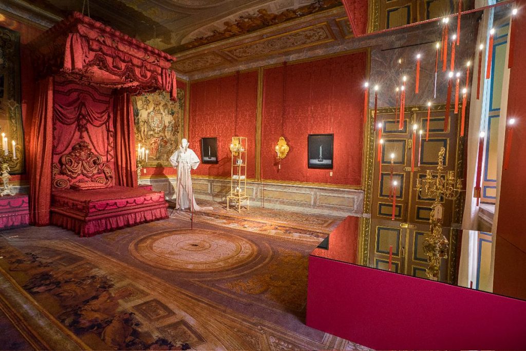 A room with a red bed and a red curtain with Flying Flames being shown in the corner of the room
