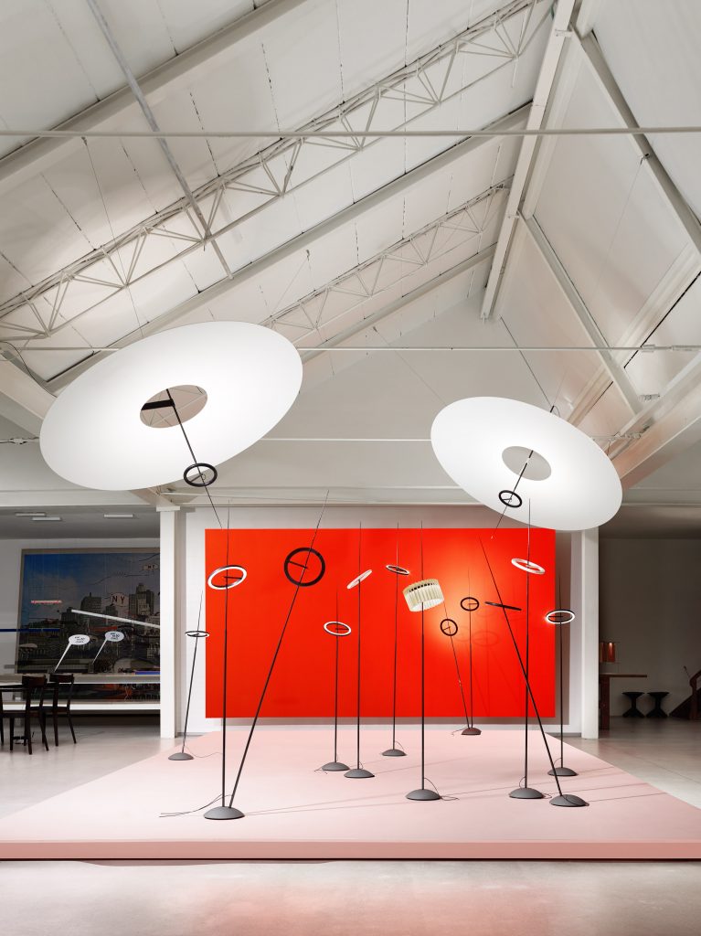 A room that has two Flying Disc lights in front of a red wall