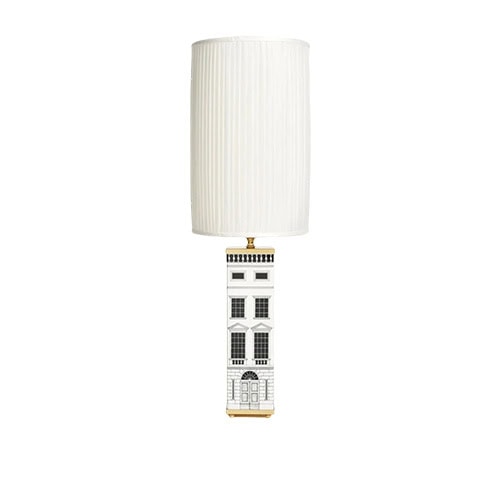 A tall lamp with a cylindrical pleated shade and an illustrated base inspired by classic architecture, bringing a whimsical yet sophisticated accent to modern interiors.