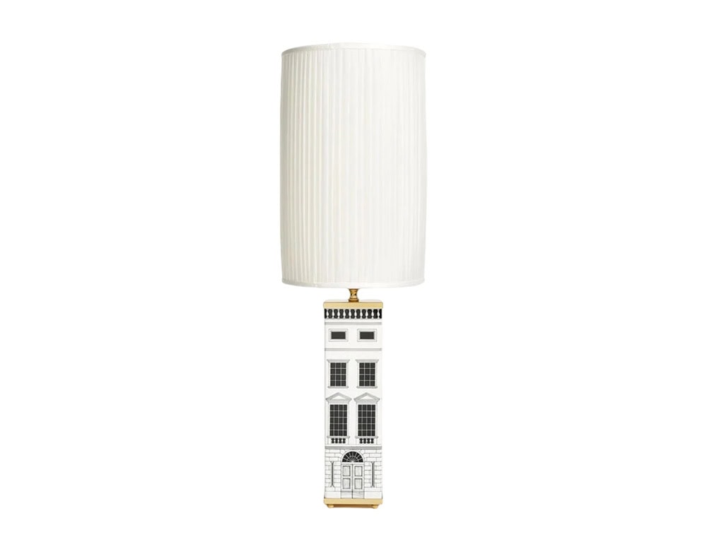 Elegant lamp featuring a tall pleated shade with a base adorned in intricate architectural motifs, blending playful artistry with refined lighting design for a striking statement piece.