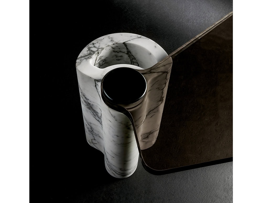 A refined coffee table combining a sculpted white marble base with a dark, textured metal top that seamlessly flows into its form, showcasing a balance of material contrast and contemporary design.