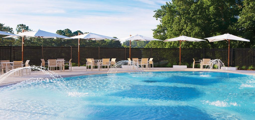five umbrellas with low base made of wood and fabric in shades of brown and white on a pool background