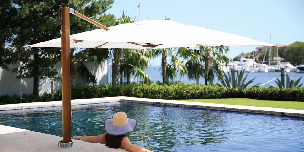 pool umbrella made of fabric and wooden base with maztiles in a brown tone and white fabric in a pool