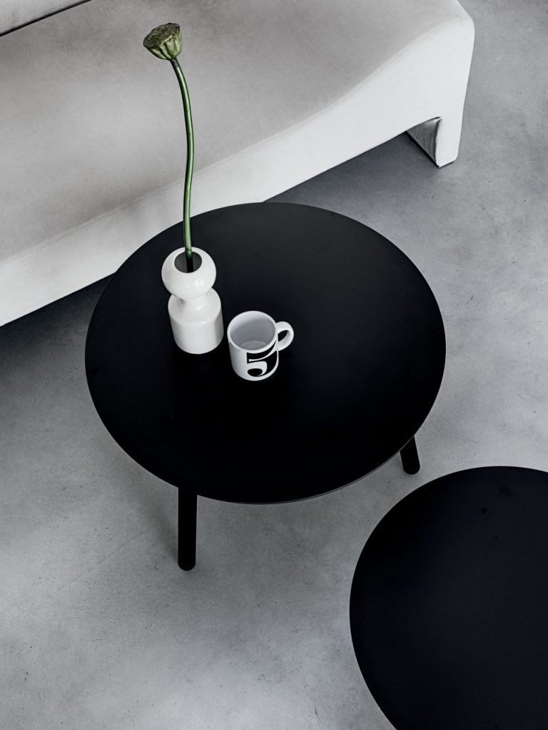 two small round wooden tables painted glossy black in a living room