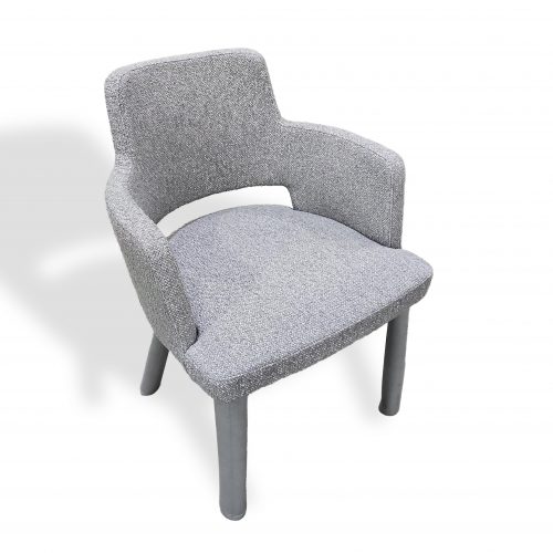 Compact upholstered armchair featuring a softly curved back and open arm design. Covered in light gray woven fabric with subtle texture and paired with matching gray legs, it brings a calm, modern feel and everyday comfort to dining or accent spaces.