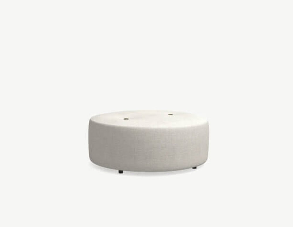A wider round outdoor pouf in light beige fabric with a soft profile, subtle tufting, and small black feet.