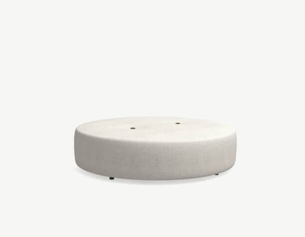n extra-wide round outdoor pouf in light beige fabric with subtle tufted accents and low black feet.