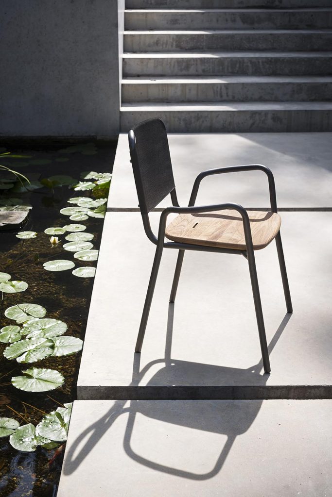 Guest One Armchair in black in front of a pond on a patio