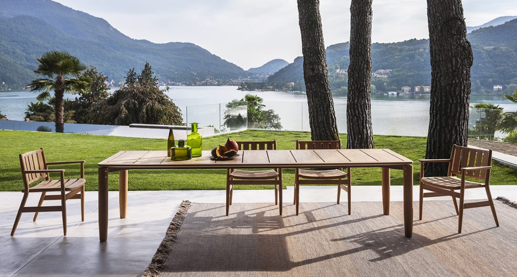 Four Levante One Armchair surrounding a wooden table with a lake and mountains in the background